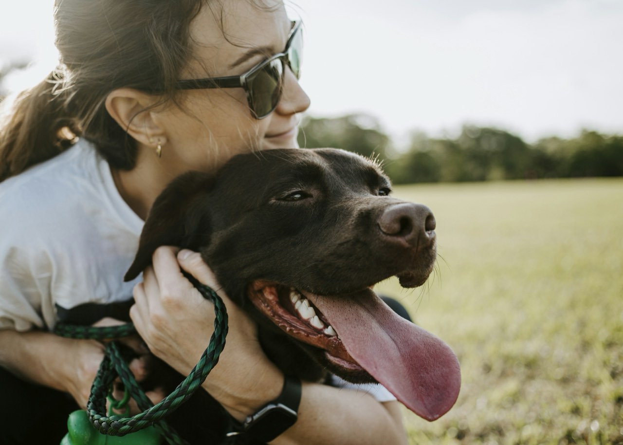 A woman hugging her dog, eyes closed