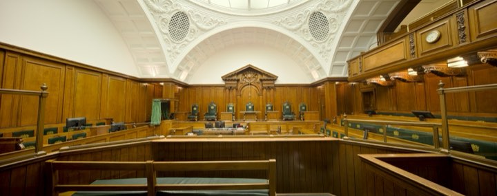 The empty public benches of a panelled courtroom, seen from the aisle
