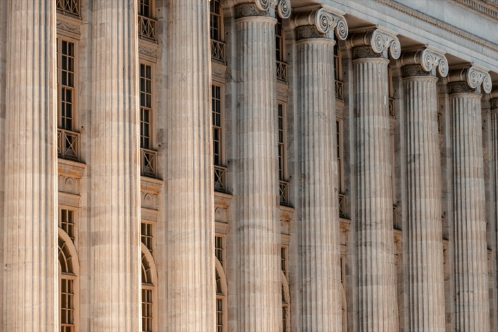 The columned front of a courthouse with a clock above the doors
