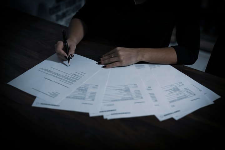 A settlement offer spread across a desk, a hand holding a pen over it