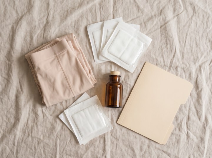 An aftercare kit laid out on linen: dressings, a small bottle and a folder