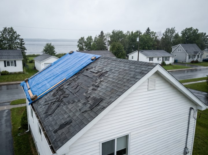 Hail-damaged roof with a tarp, before work